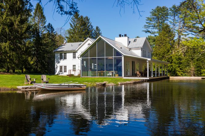 A photo of a renovated white farmhouse perched on a creek sold by the Upstate Curious real estate team 